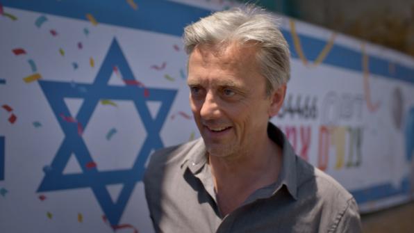 "Life-Sized City" host Mikael Colville-Andersen standing with the flag of Israel in the background. | "Life-Sized City: Tel-Aviv"