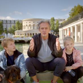 "Life-Sized City" host Mikael Colville-Andersen sits beside a body of water in Paris with two children and a dog.