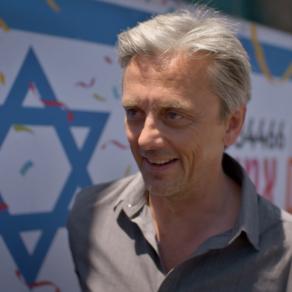 "Life-Sized City" host Mikael Colville-Andersen standing with the flag of Israel in the background. | "Life-Sized City: Tel-Aviv"